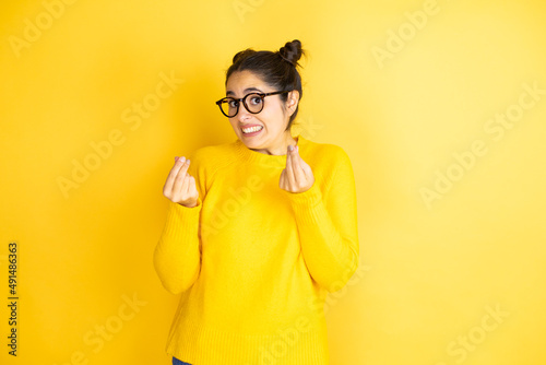 Fotografie Young beautiful woman wearing casual sweater over isolated yellow background doi