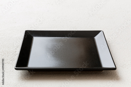 Perspective view of empty square plate on cement background. Empty space for your design