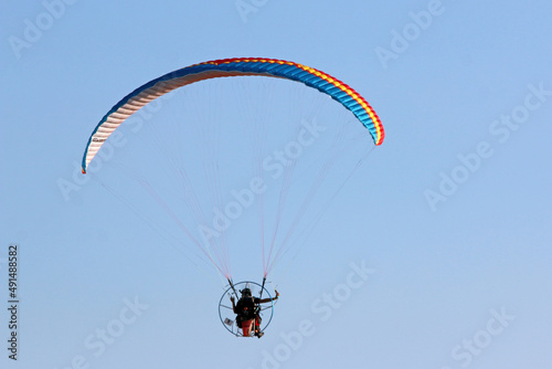 Paramotor pilot flying in a blue sky 