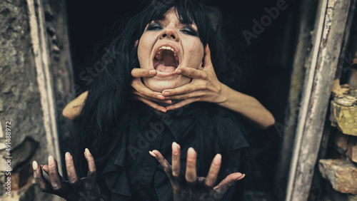 Tablou pe pânză Emotional woman witch in black strangling hands she shouts