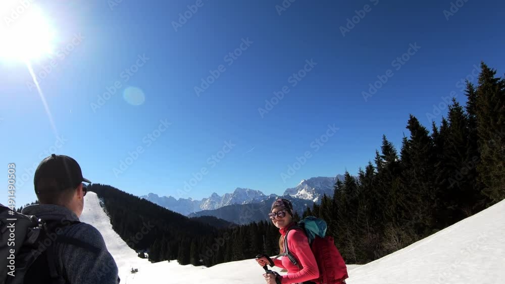 Happy couple walking in snow shoes on Dreilaendereck (Pec, Monte Forno) in the Karawanks in Carinthia, Austria. Winter wonderland. Border Austria, Slovenia, Italy. Sunny. Outdoor activities. Fresh sno