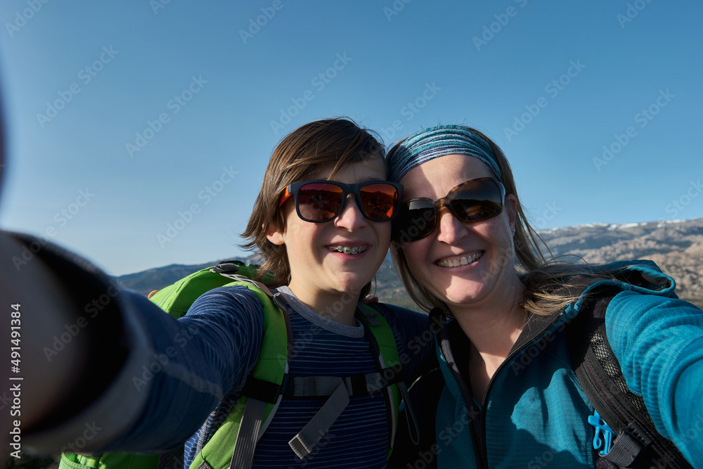 A Teenage boy with braces and mother taking selfie during hiking in nature A Teenage boy with braces and mother taking selfie during hiking in nature