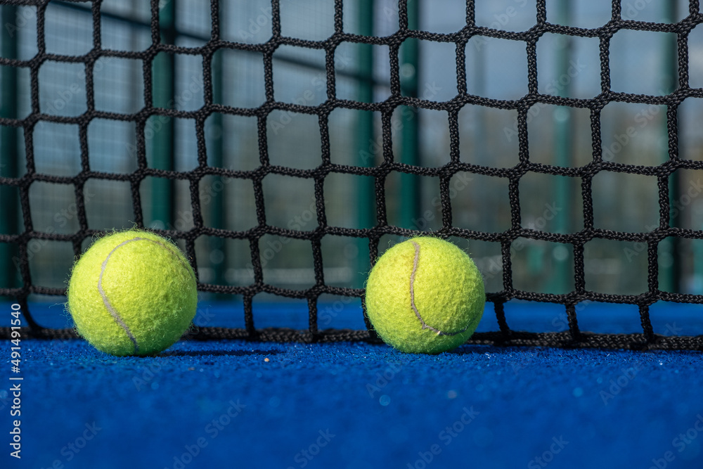 Two paddle balls on the surface of a blue paddle court.