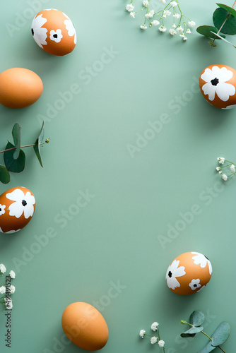Photography Frame of Easter eggs and flowers on pastel green background