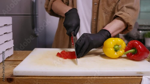 hands of a cook who slices Bulgarian pepper on a cutting board