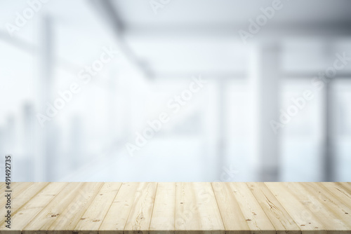 Blank wooden desk with light empty office room with big window on background, mock up © Pixels Hunter