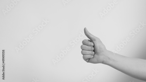 Hand is doing like or thumbs up sign on white background.Black and white picture.