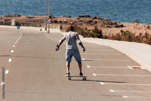 A man playing figure skating on a rural road in the sun on a bright day  Play surf skate near coast