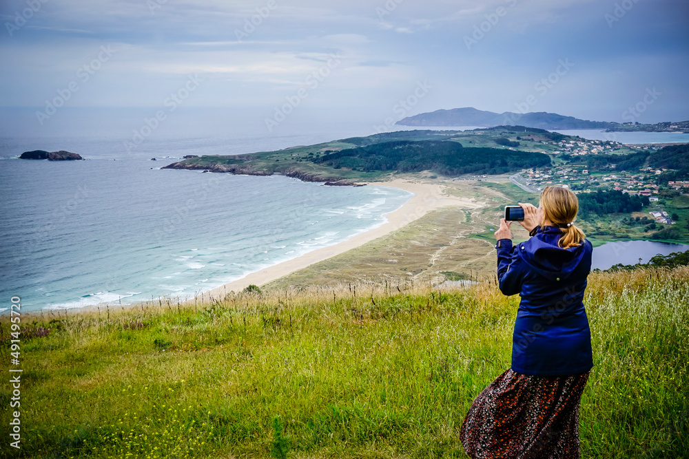 Young and beautiful woman taking photos with the mobile on the coast of Galicia Young and beautiful woman taking photos with the mobile on the coast of Galicia