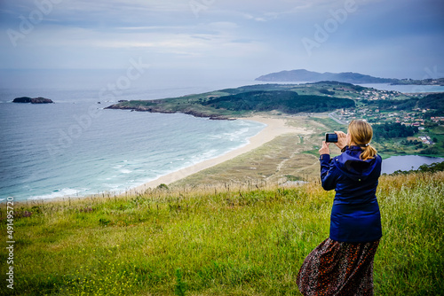 Young and beautiful woman taking photos with the mobile on the coast of Galicia