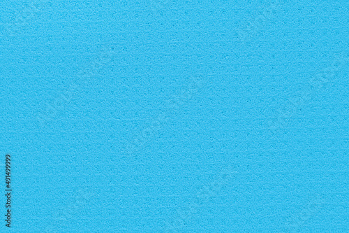 Porous blue background from a kitchen sponge. Blue background made of soft synthetic material with a chaotic close-up of pores. Free space for ads and text