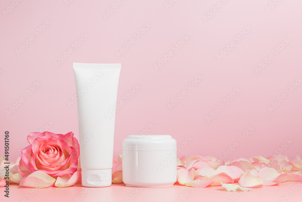 Face cream unbranded tube and cream bottle mockup with rose flower and petals on pink background, copy space, face skin care containers for natural cosmetic design and branding Face cream unbranded tube and cream bottle mockup with rose flower and petals on pink background, copy space, face skin care containers for natural cosmetic design and branding