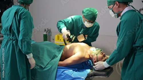 Team of doctor helping by AED defibrillation with accident injured patient unresponsive in emergency room