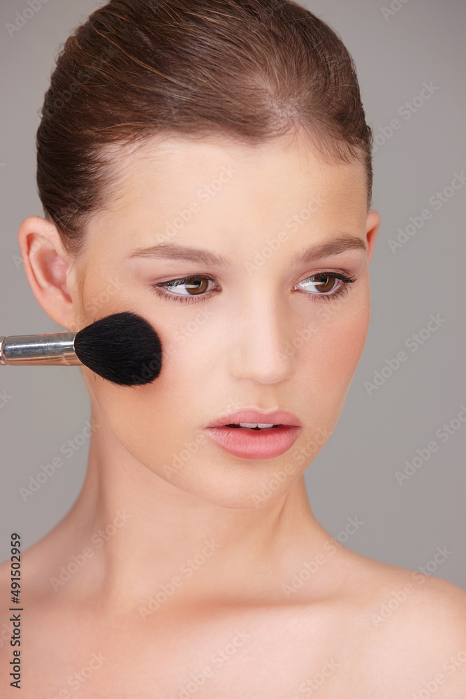 Enhancing her natural beauty with a touch of blush. Studio shot of a beautiful woman applying blush to her cheeks. Enhancing her natural beauty with a touch of blush. Studio shot of a beautiful woman applying blush to her cheeks.