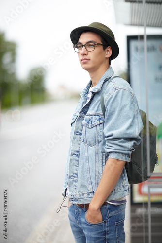 Waiting along the bus route. Hip young guy standing at a bus stop with his hands in his pockets.