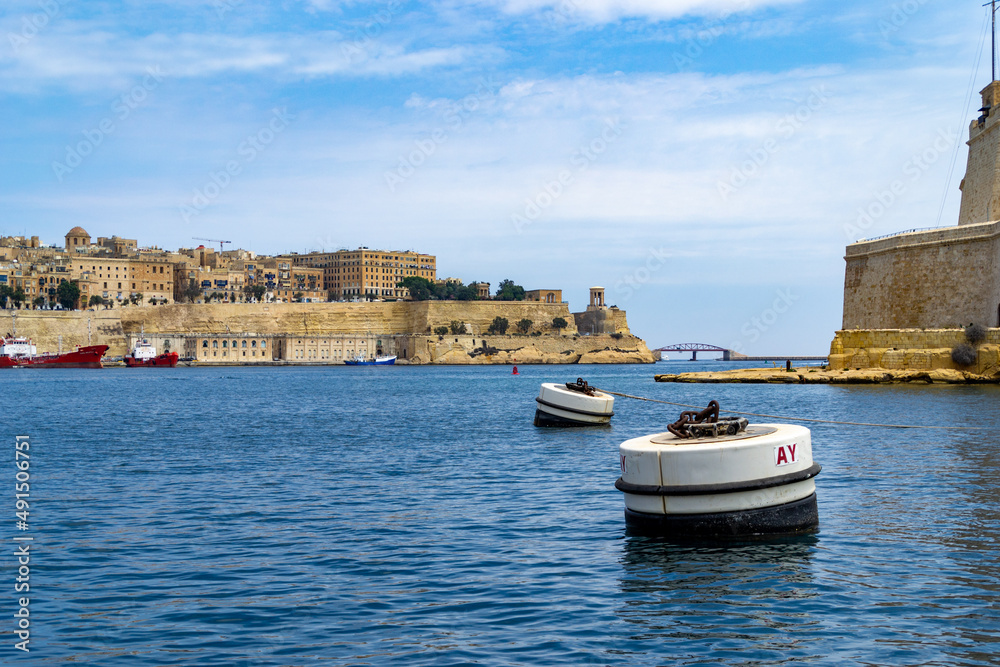 The Grand Harbour in Malta with the tip of Fort St. Angelo and the City of Valletta with the Lower Barrakka Gardens, Pixkerija and Siege Bell Memorial.