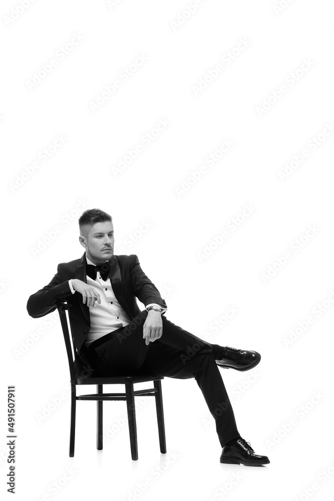 handsome man in tuxedo sitting on chair handsome man in tuxedo sitting on chair