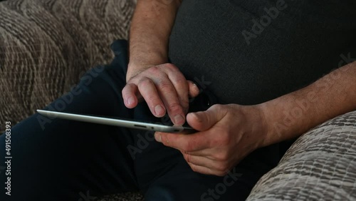 Close-up of an elderly man's old hands using a computer tablet.