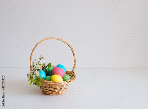 Easter basket with eggs on a white background. Beautiful Easter composition with spring flowers. Copy space.