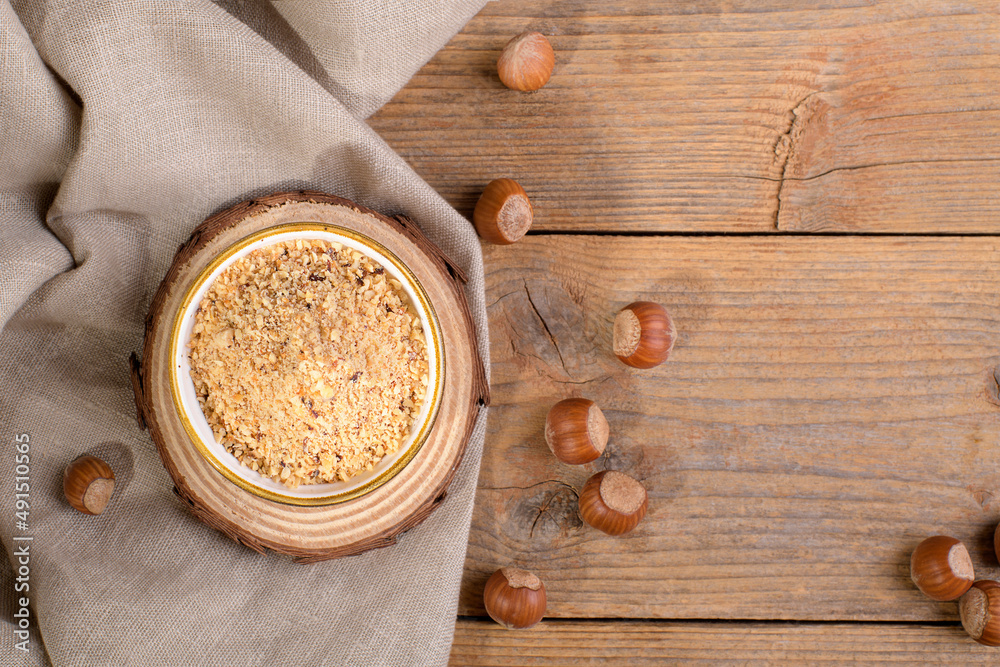 Raw Organic Ground Hazelnut Flour in a Bowl with whole nuts on rustic wooden background. Alternative nut flour for keto diet and gluten free food. Paleo and ketogenic diet baking cooking concept above