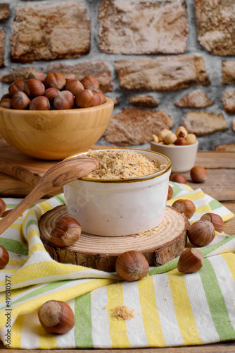 Raw Organic Ground Hazelnut Flour in a Bowl with whole nuts on rustic wooden background. Alternative nut flour for keto diet and gluten free food. Paleo and ketogenic diet baking cooking concept