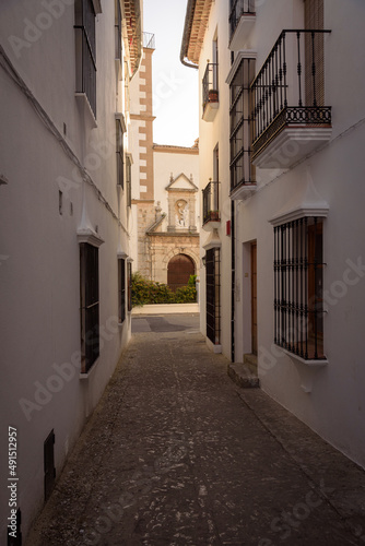 Fototapeta Naklejka Na Ścianę i Meble -  Street in the old town in the white village of Grazalema with the parish of the incarnation in the background, Natural Park of Grazalema mountain range, Cadiz, Andalusia, Spain