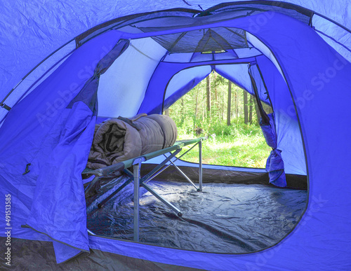 camping with rolled up sleeping bag and off the ground bed cot in blue tent in the mountains summer fun, campground photo