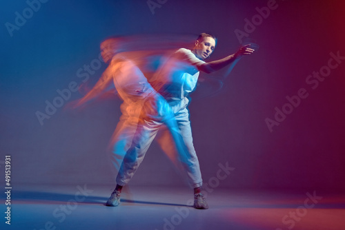 Young stylish girl in action, motion, dancing hip-hop. Breakdancer in colourful neon light at dance hall. Long exposure