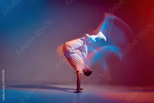 Young girl dancing contemporary dance in neon studio light. Acrobatic dancer. Breakdance school ad. Long exposure photo