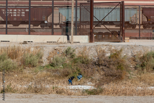 Two men hide in the bushes to avoid being caught by immigration agents at the US-Mexico border in Ciudad Juarez Chihuahua Mexico.