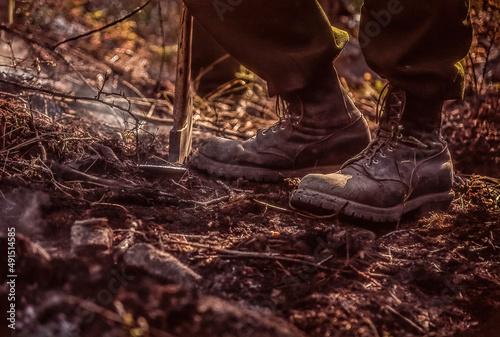 A wildland firefighter's boots on smoldering terrain