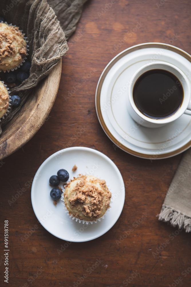 Top View of Blueberry Muffin and Coffee on a Wooden Table; Wooden Bowl of Blueberry Muffins