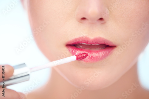 Pretty in pink. A young woman applying pink lipstick with an applicator.