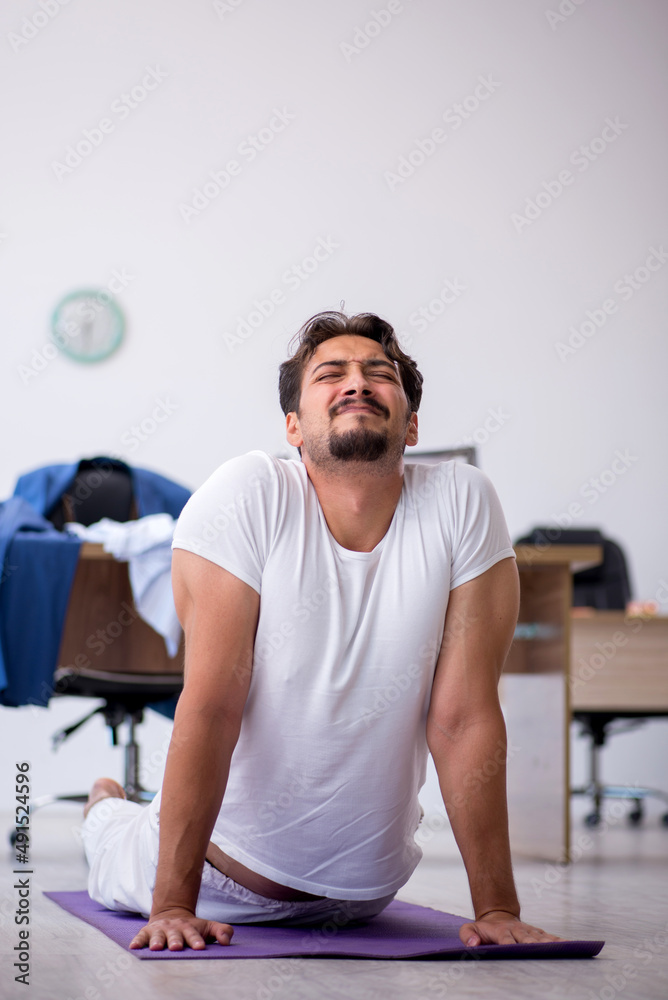 Young male employee doing sport exercises in the office Young male employee doing sport exercises in the office