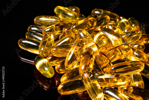 Close up of Omega 3 gel capsule on a reflective black background