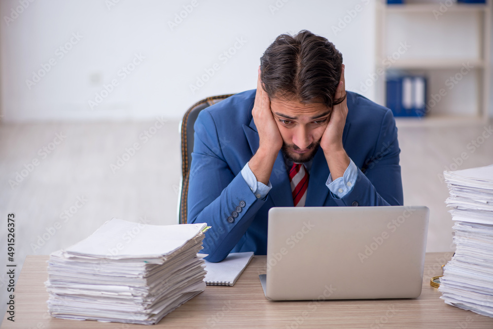Young male employee and too much work in the office Young male employee and too much work in the office