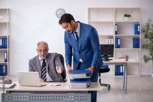 Old male boss and young male employee working in the office