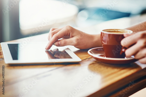 Nothing better than great coffee and wifi. Cropped shot of a woman using a digital tablet in a coffee shop.