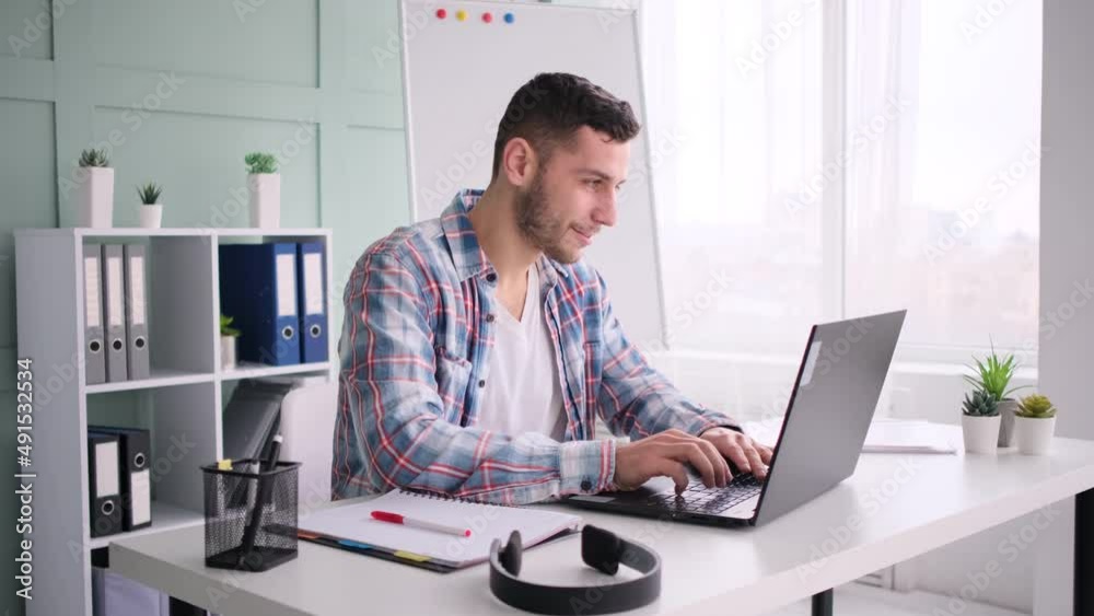 Young man working in home office, using laptop Young man working in home office, using laptop