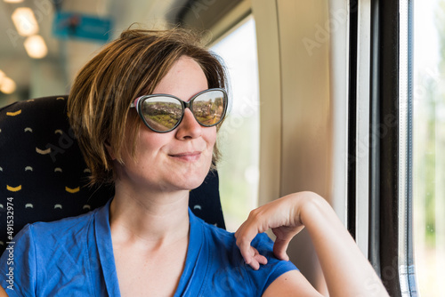 Zellik, Flemish region - Belgium - Attractive thirty year old woman with sunglasses looking out of the window of a local train photo
