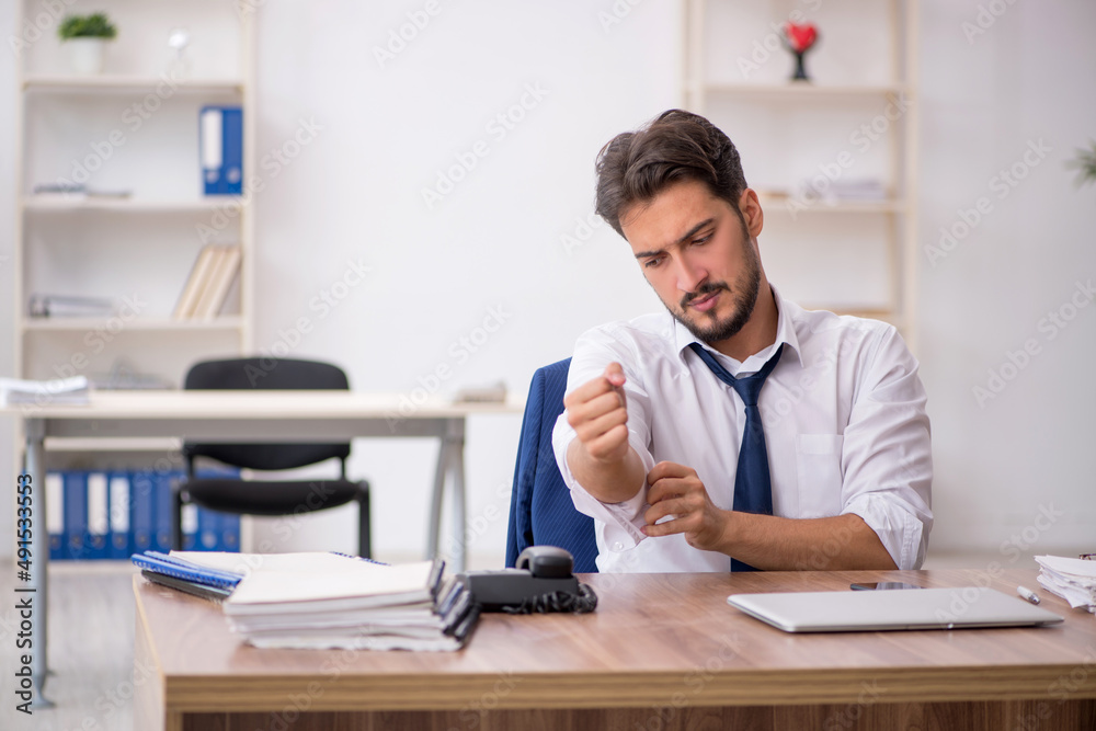 Young male employee unhappy with excessive work in the office Young male employee unhappy with excessive work in the office