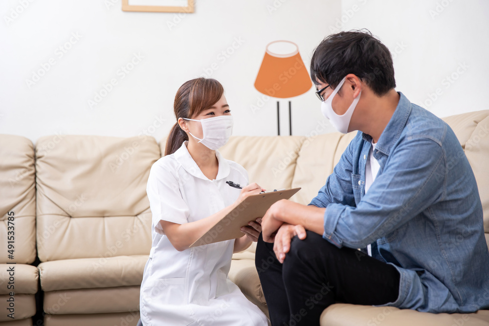 Obraz premium 問診票に記入する看護師と患者（マスク）