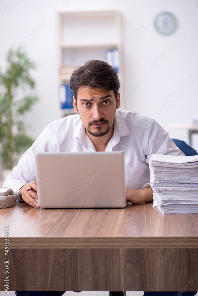 Young male employee and too much work in the office Young male employee and too much work in the office