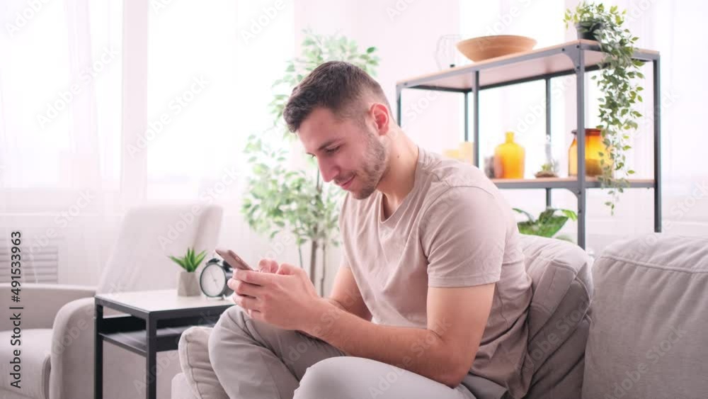Man chatting on smartphone sitting on sofa Man chatting on smartphone sitting on sofa