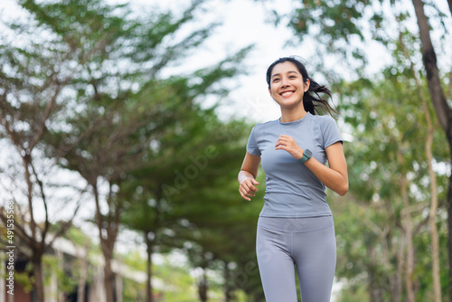 Fotografie Happy slim woman wearing sportswear jogging in the city at sunrise