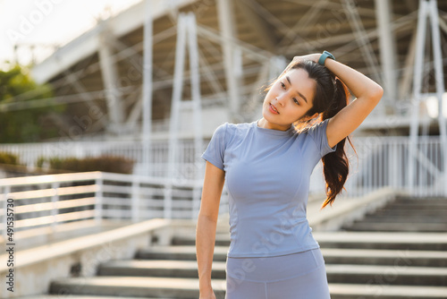 Beautiful asian woman wearing sportswear warming up front of sport stadium. Confident and powerful woman stretching before Workout exercise in the morning. Healthy and active lifestyle concept.