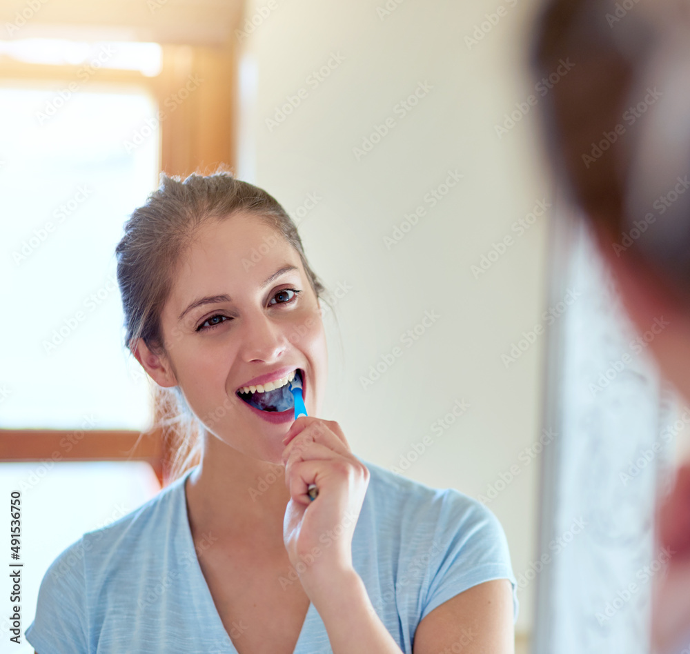 Oral health reflects your overall health. Cropped shot of a young woman brushing her teeth in a mirror. Oral health reflects your overall health. Cropped shot of a young woman brushing her teeth in a mirror.