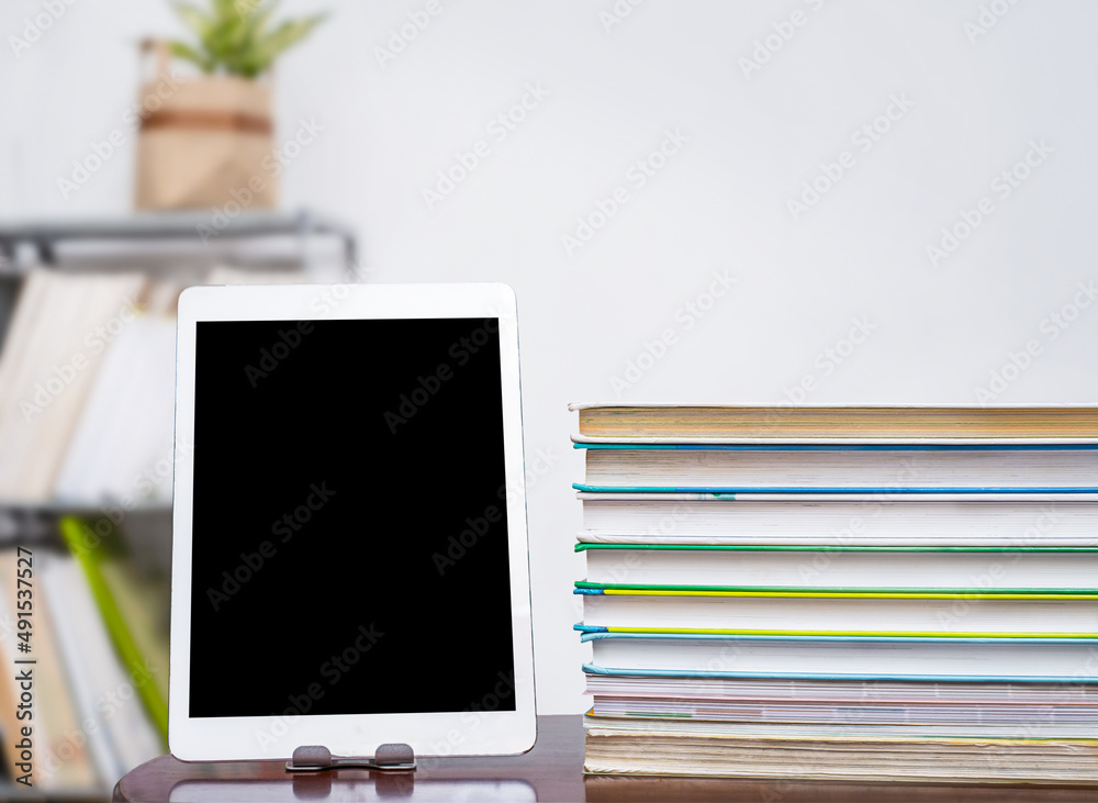 Tablet and stack of books on table Tablet and stack of books on table