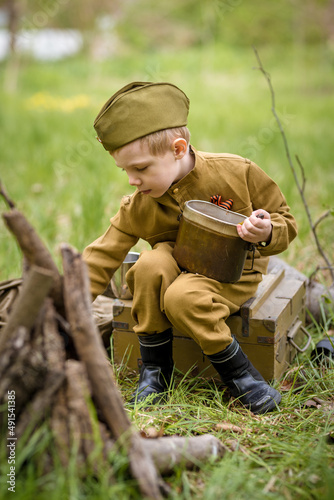 a small child in a beautiful military victory uniform, playing in nature and eating soldier porridge