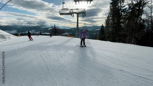 Skiers going downhill in a ski resort, active rest in winter mountains, extreme shooting in motion